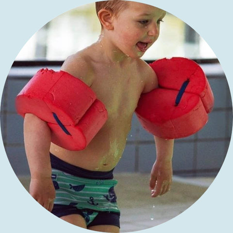 Baby med røde vinger i svømmehal.